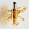 The new refillable Elixir Ultime is surrounded by beautiful golden hair oil drops and texture.