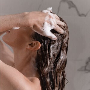Consejos de Kérastase para protegerse del agua dura - modelo de uso de shampoo espumante.